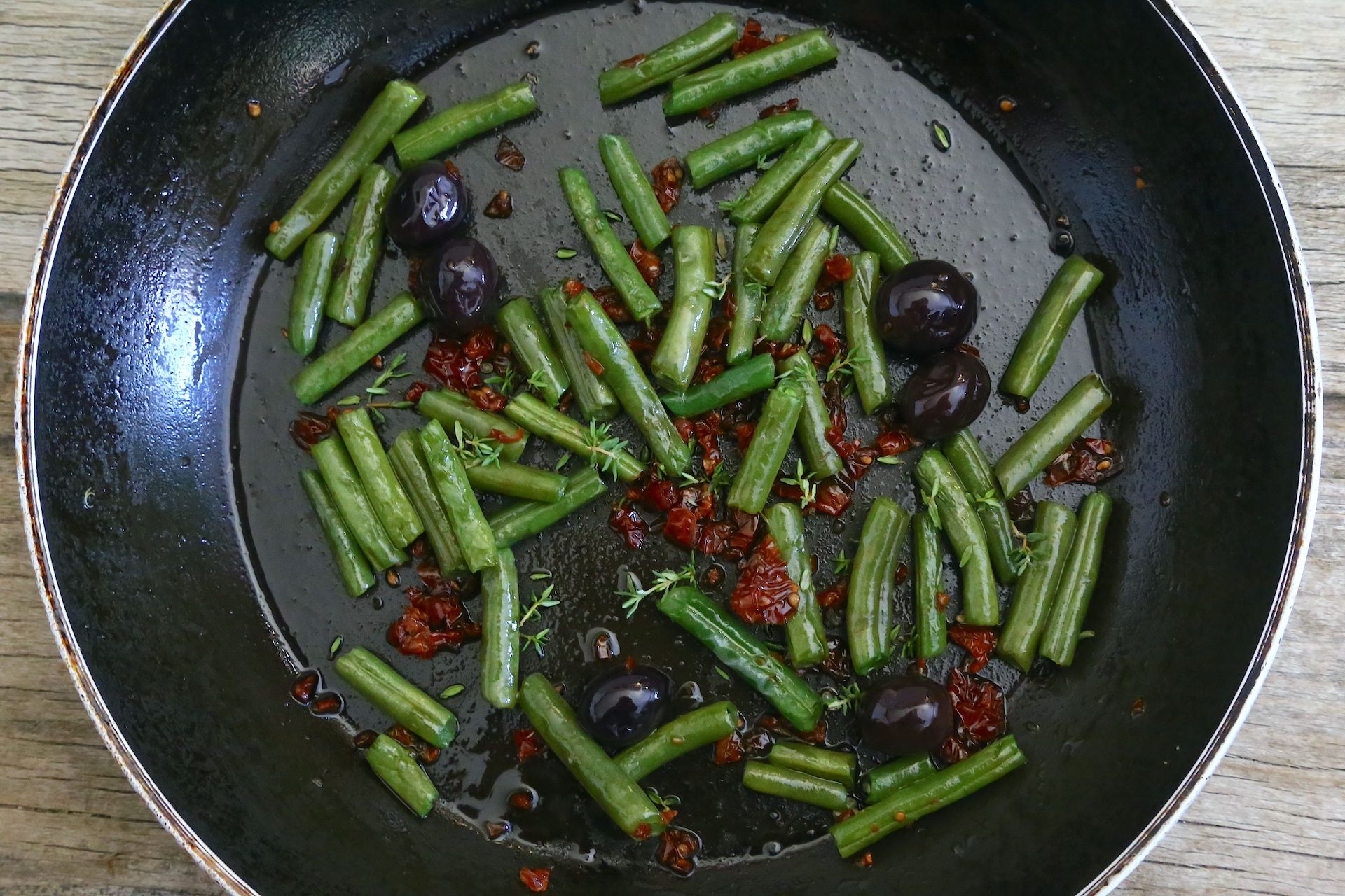 Fagiolini, pomodorini secchi, olive e timo si insaporiscono in padella con l’aglio © Beatrice Spagoni 